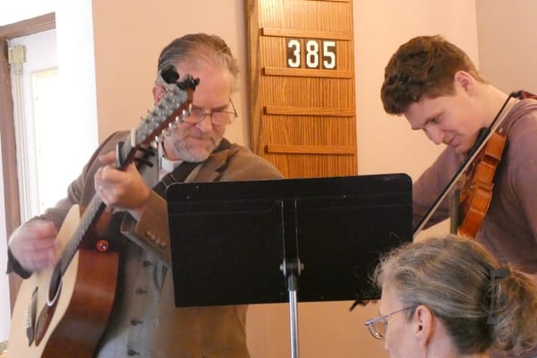 Musicians playing guitar and violin during worship at the 2022 FORC Synod