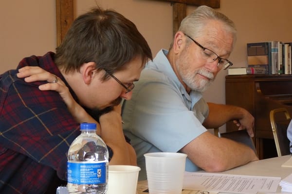 Two attendees in conversation at a synod session table